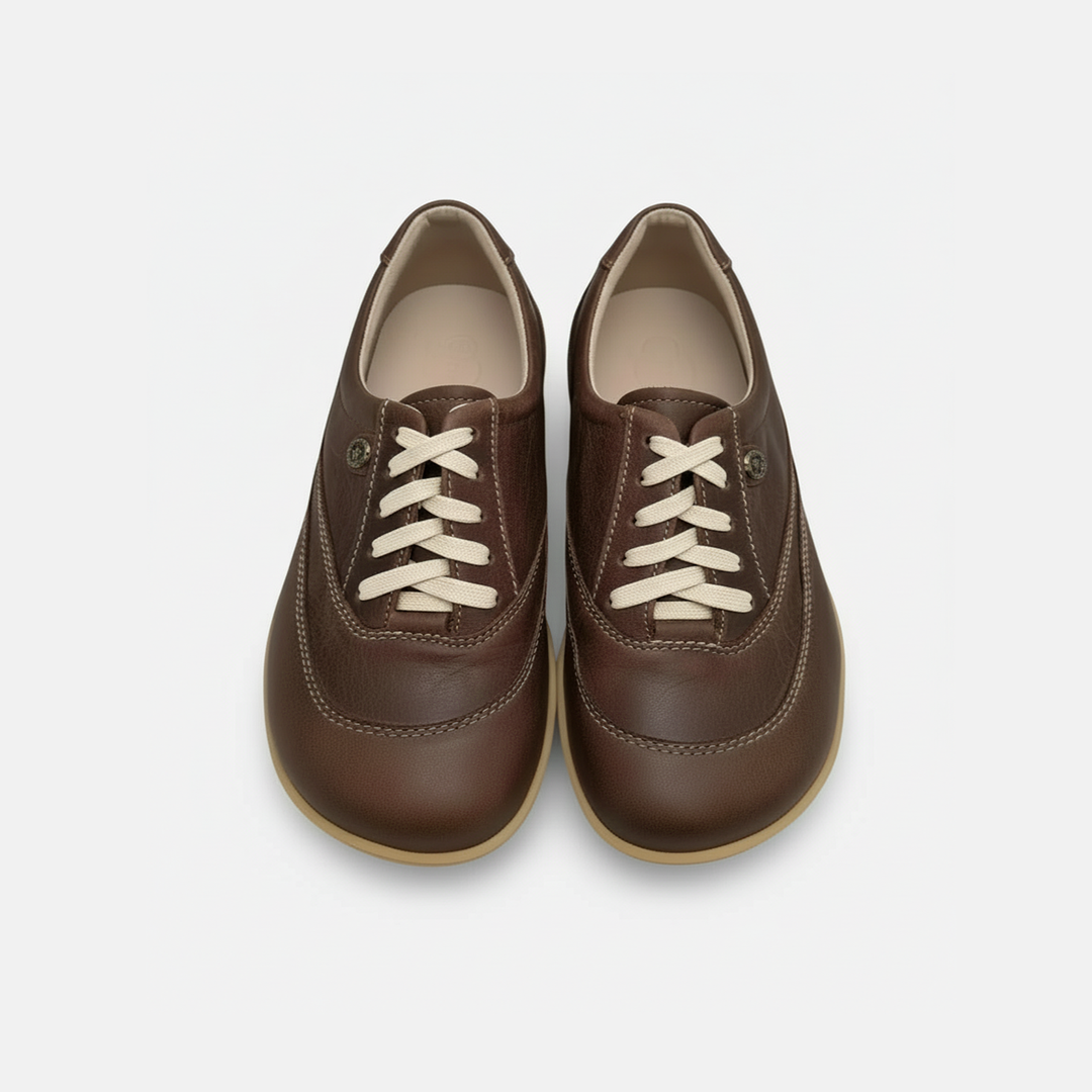Pair of brown leather shoes with white laces on a light gray background