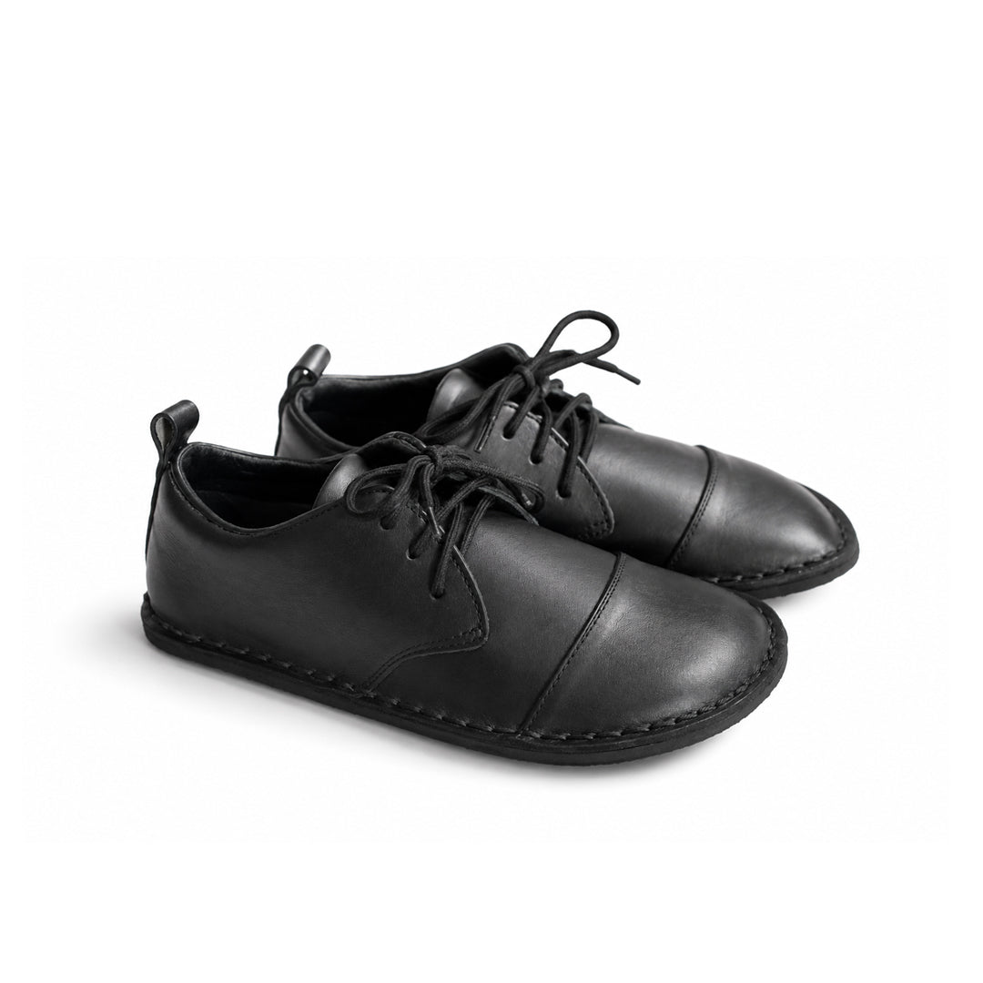 A pair of black leather lace-up shoes with a cap toe and decorative stitching, shown on a clean white background.