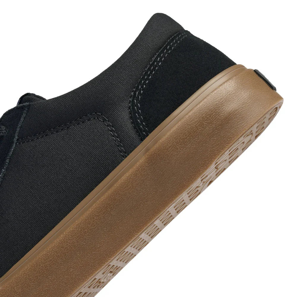 Close-up of black sneaker with brown gum sole and textured sole pattern