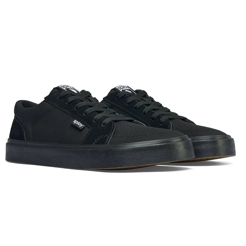 Pair of black low-top canvas sneakers with thick rubber sole and laces on white background