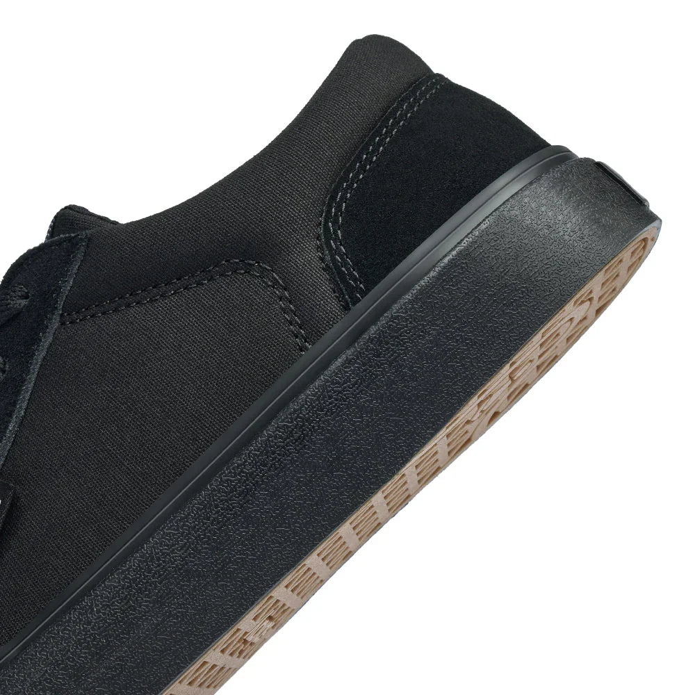 Close-up of black sneaker heel with textured sole and stitched microfiber upper