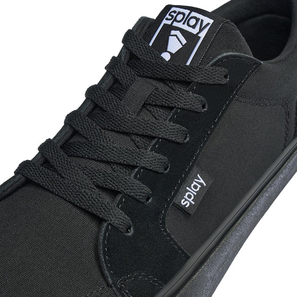 Close-up of black Splay sneaker with nylon and suede upper, black laces, and branded tags