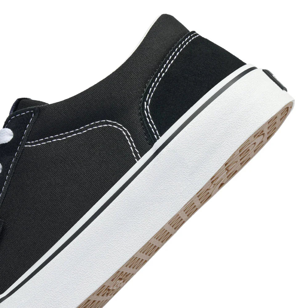 Close-up of black canvas sneaker with white stitching and rubber sole showing waffle tread pattern