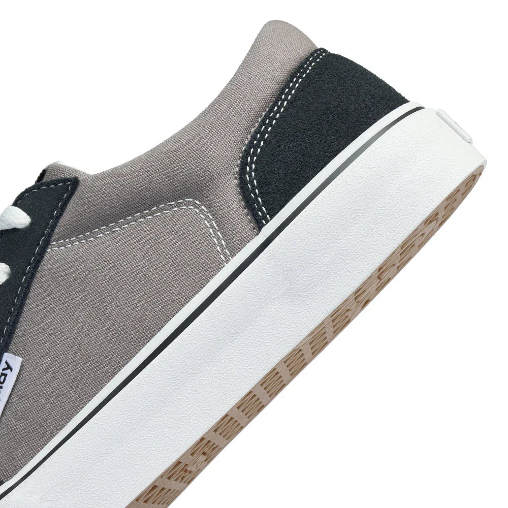 Close-up of gray and black casual sneaker with white laces and thick white sole on white background