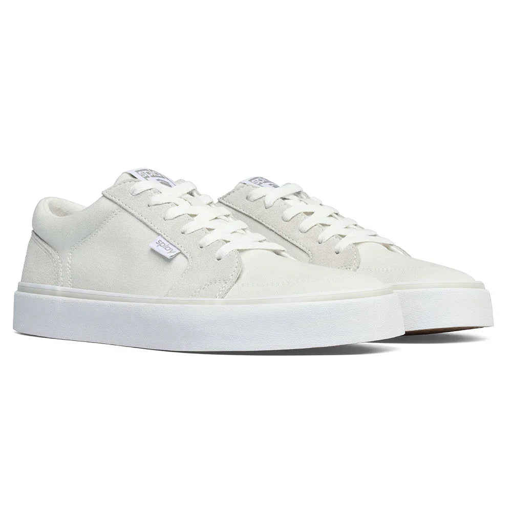 Pair of white low-top casual sneakers with thick sole and laces on white background