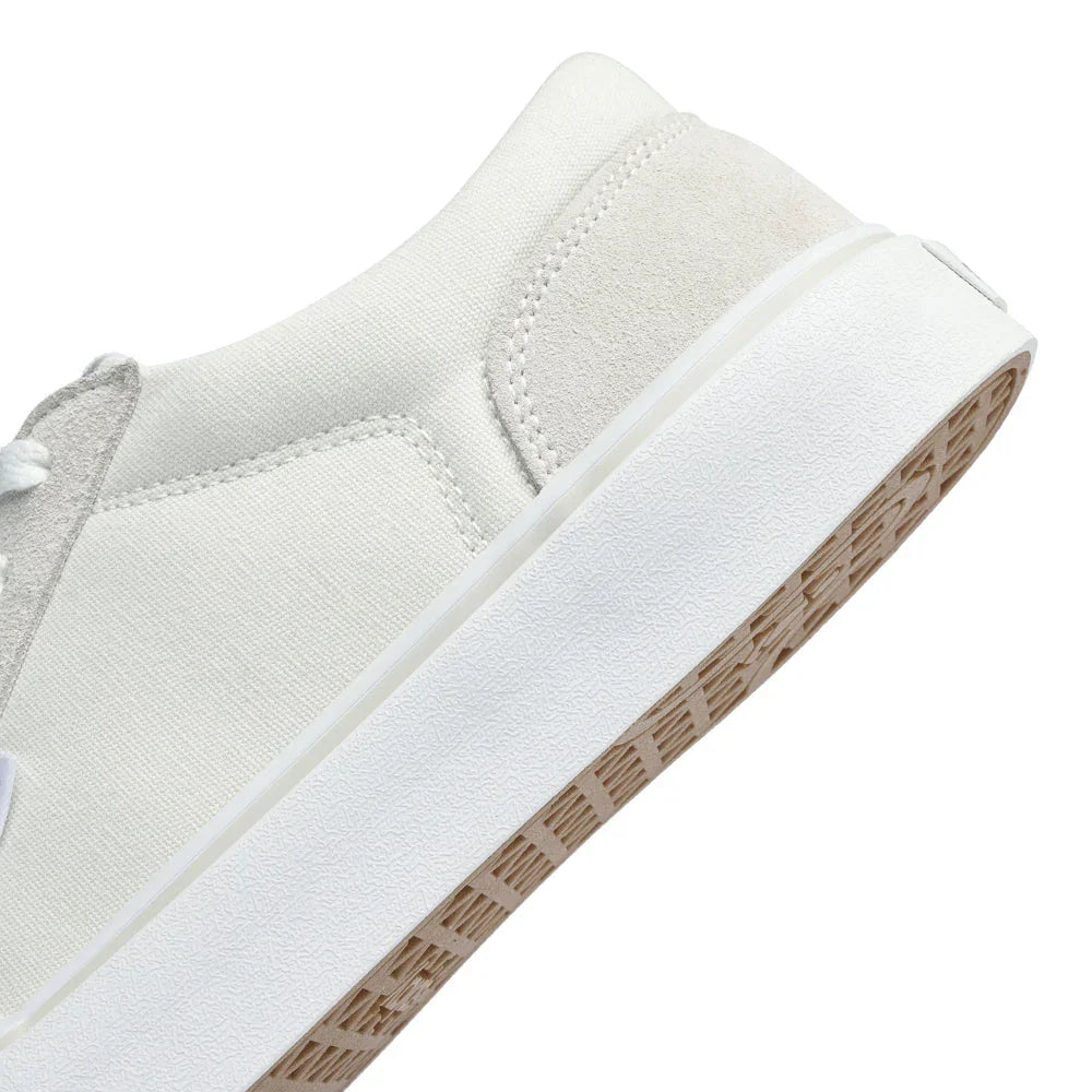 Close-up of white canvas and suede sneaker heel with textured white sole and gum outsole