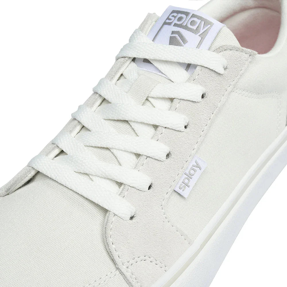 Close-up of white Sply sneaker with canvas and suede upper, white laces, and branded logo tag
