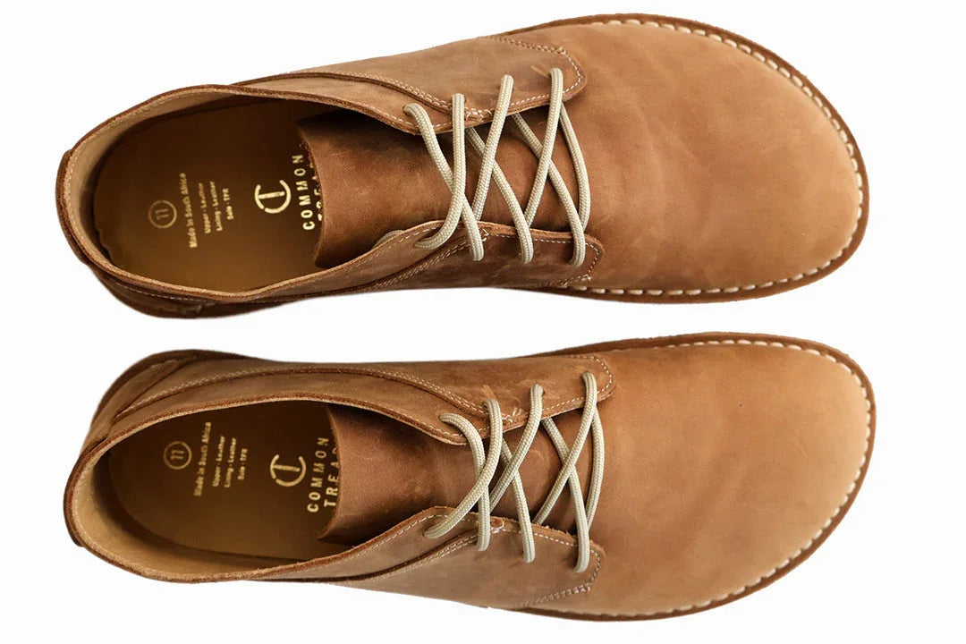 Top view of tan leather desert boots with beige laces on white background