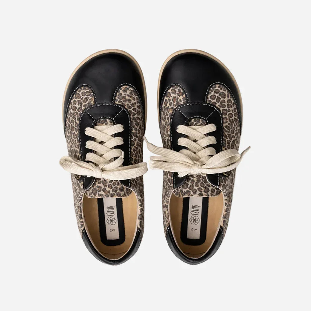 Pair of black sneakers with leopard print pattern on a white background