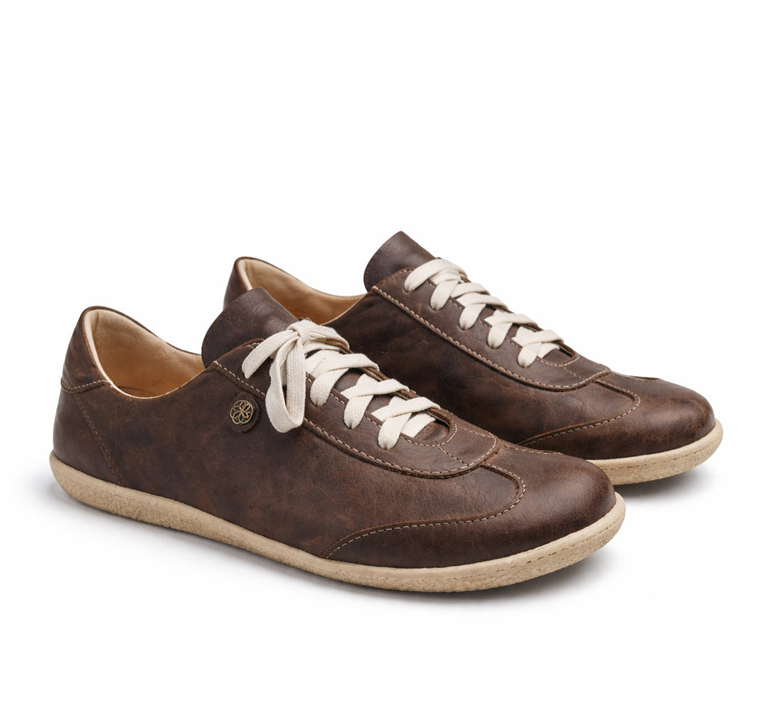 Pair of brown leather sneakers with white laces on a white background