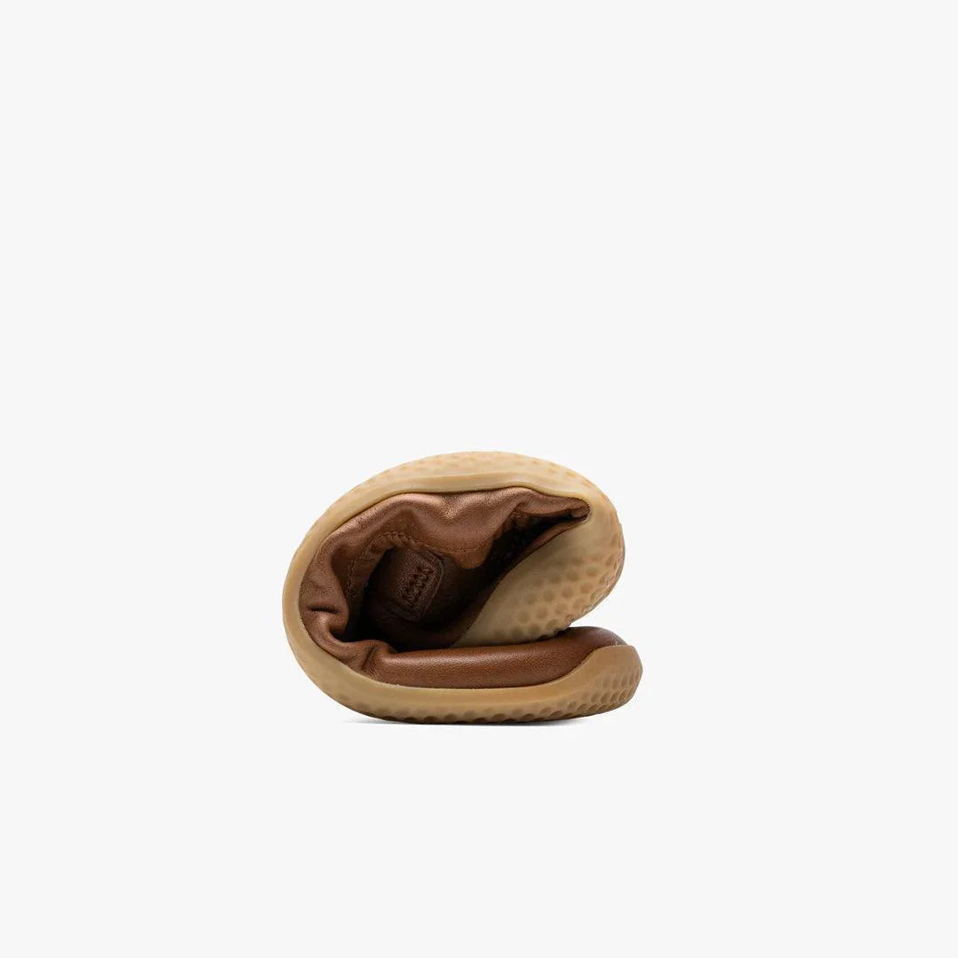 Folded tan barefoot shoe with flexible sole on white background, eco-friendly footwear