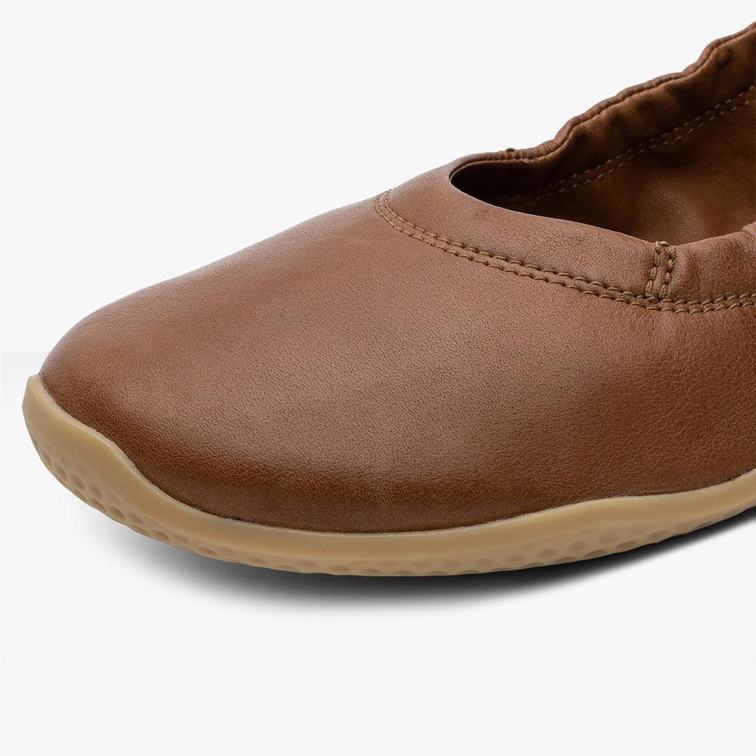 Tan women's barefoot ballerina shoe with flexible sole on white background