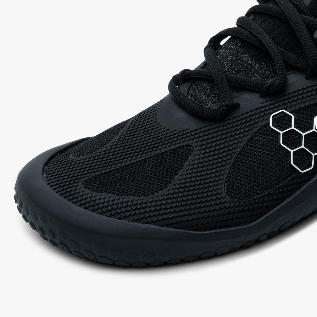 Close-up of black Vivobarefoot Motus Strength men's sneaker with textured upper and hexagonal logo